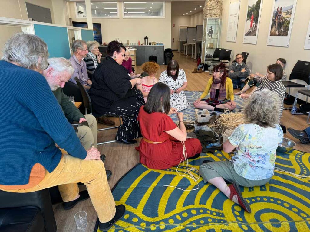 A photo of people in a yarning circle doing craft and talking about local action.